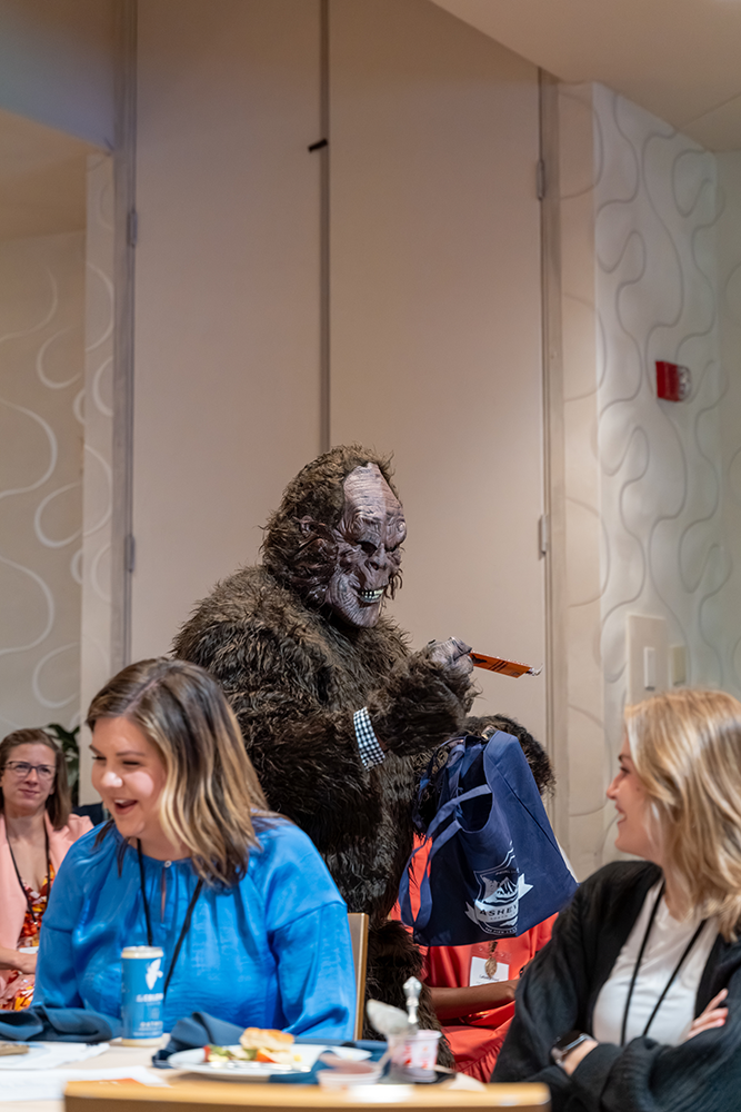 ACE member dressed as Bigfoot at 2023 ACE conference promotes the next annual conference to the audience.
